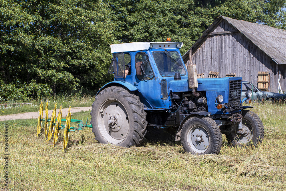 natural lighting. The driver of a blue tractor cleans hay and oats. close-up natural lighting. The driver of a blue tractor cleans hay and oats. close-up