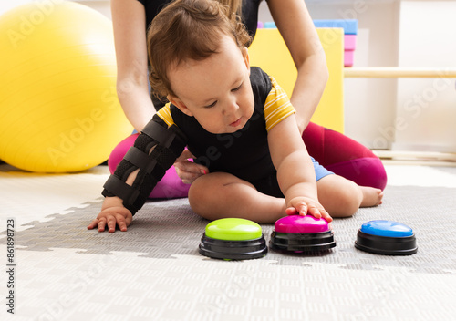 Toddler boy with damage to the central nervous system engages in rehabilitation therapy at children rehab center photo