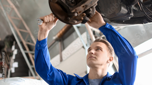 Male mechanic fixing car in...