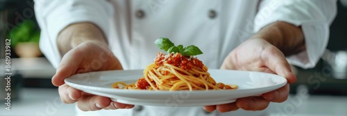 Panel kuchenny z motywem A professional chef's hands presenting a plate of perfectly cooked spaghetti with tomato sauce in an all-white kitchen, wearing a chef's jacket, restaurant plate. Italian cuisine menu