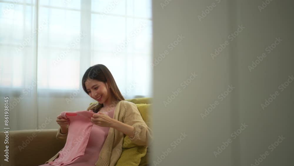 Happy pregnant woman holding baby pink bodysuit while caressing her belly at home, happy motherhood waiting for childbirth, family planning and pregnancy with insurance for child health.
Happy pregnant woman holding baby pink bodysuit while caressing her belly at home, happy motherhood waiting for childbirth, family planning and pregnancy with insurance for child health.