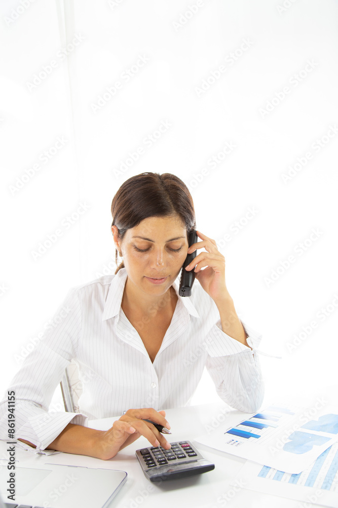 Good business talk. Cheerful young beautiful woman in glasses talking on mobile phone and using laptop with smile while sitting at her working place Good business talk. Cheerful young beautiful woman in glasses talking on mobile phone and using laptop with smile while sitting at her working place