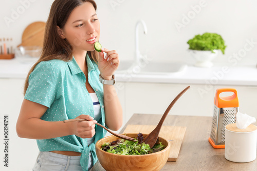 Young woman eating cucumber...