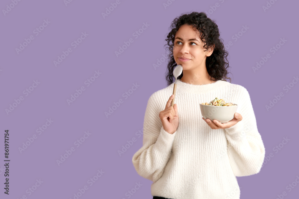 Thoughtful young woman with bowl of cereal rings and spoon on lilac background Thoughtful young woman with bowl of cereal rings and spoon on lilac background