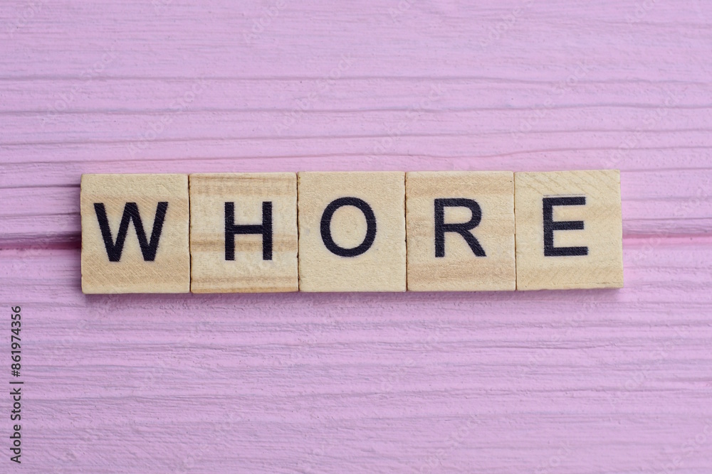 word whore from small gray wooden letters lies on a pink background word whore from small gray wooden letters lies on a pink background