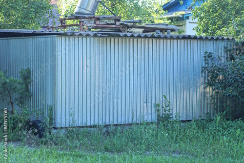 part of grey metal fence wall in green grass and vegetation on rural street