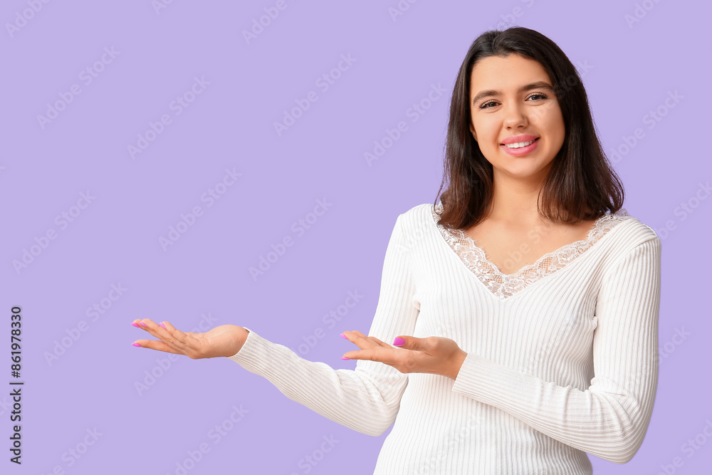 Young happy smiling woman pointing at something on lilac background Young happy smiling woman pointing at something on lilac background