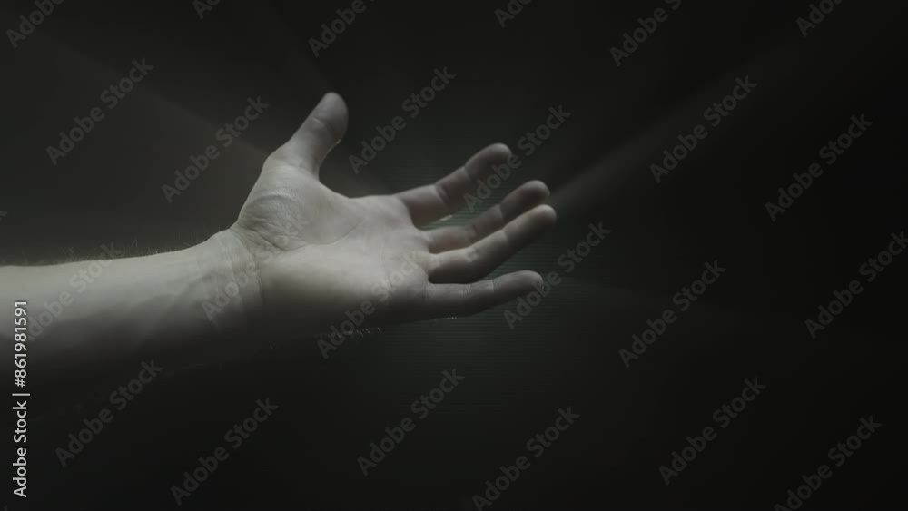 A hand reaching towards a beacon of light amidst darkness A hand reaching towards a beacon of light amidst darkness