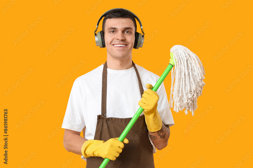 Male janitor with mop and headphones on yellow background Male janitor with mop and headphones on yellow background