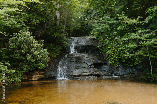 Beautiful large waterfall between green trees in the mountains. Mountain landscape with a waterfall on a summer day. Wildcat Waterfall, Great Smokey Mountains, South Carolina, USA.  photo