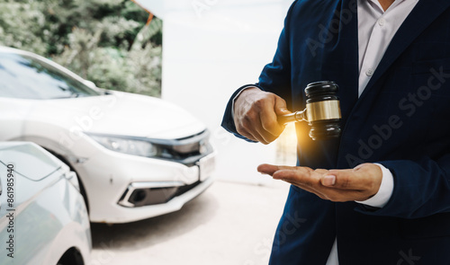 businessman in a suit and a lawyer, holding a wooden gavel, stand in front of a car, discussing legal aspects like citations, liability, and negligence related to a traffic violation...