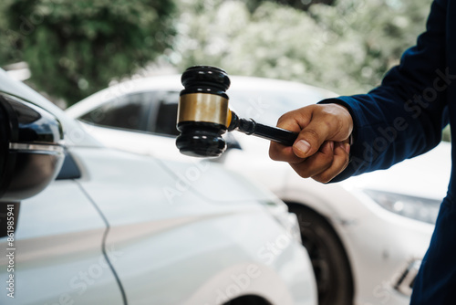 Fotografie businessman in a suit and a lawyer, holding a wooden gavel, stand in front of a car, discussing legal aspects like citations, liability, and negligence related to a traffic violation