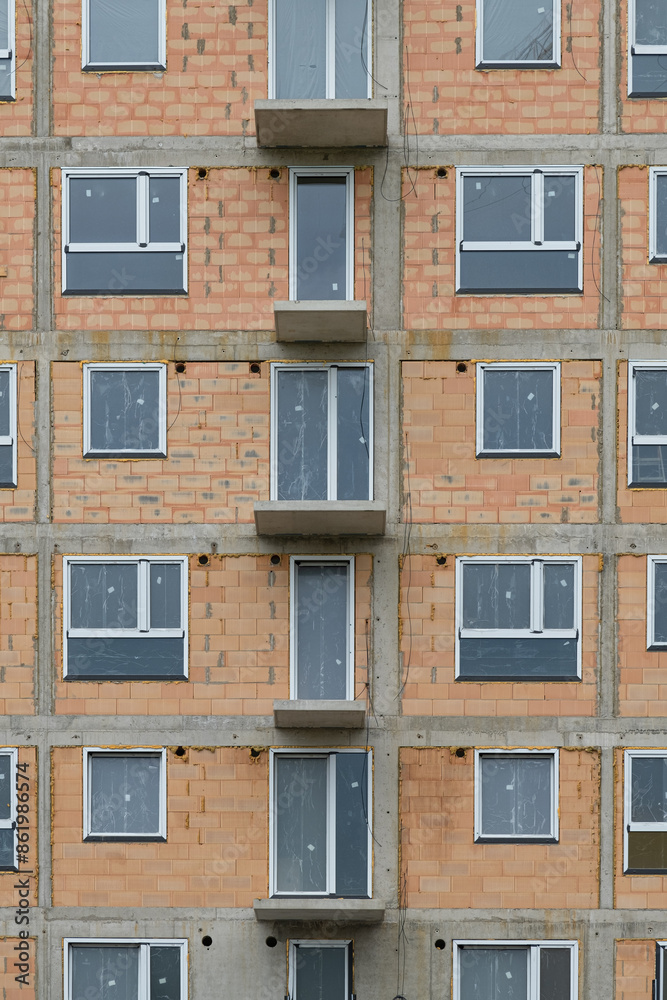 Fototapeta premium new building the real estate market. New construction building. red clay ceramic thermo brick multi-story building before insulation and cladding. New windows installed,