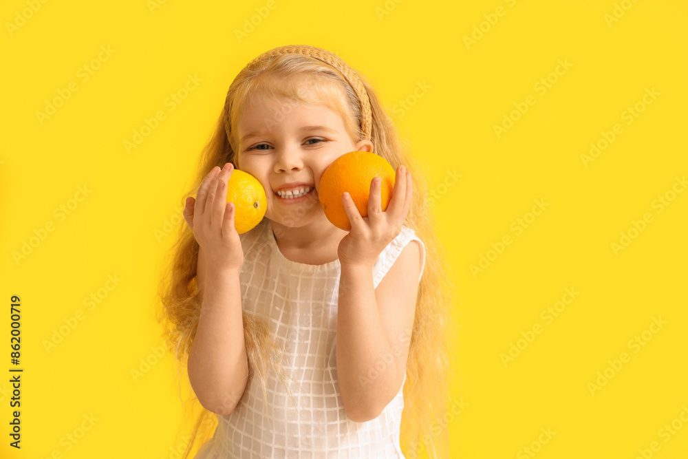Adorable little girl with orange and lemon on yellow background Adorable little girl with orange and lemon on yellow background