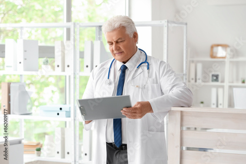 Mature doctor with clipboar...