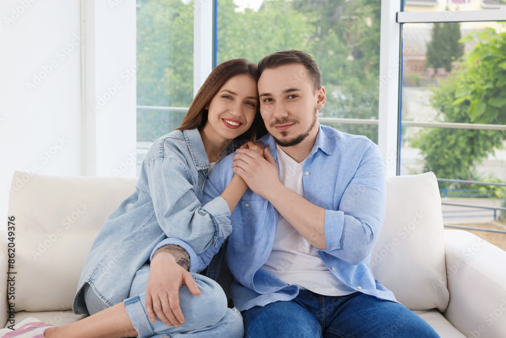 Happy couple holding hands on sofa at home Happy couple holding hands on sofa at home