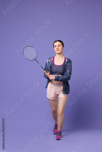 Young woman with badminton racket on purple background