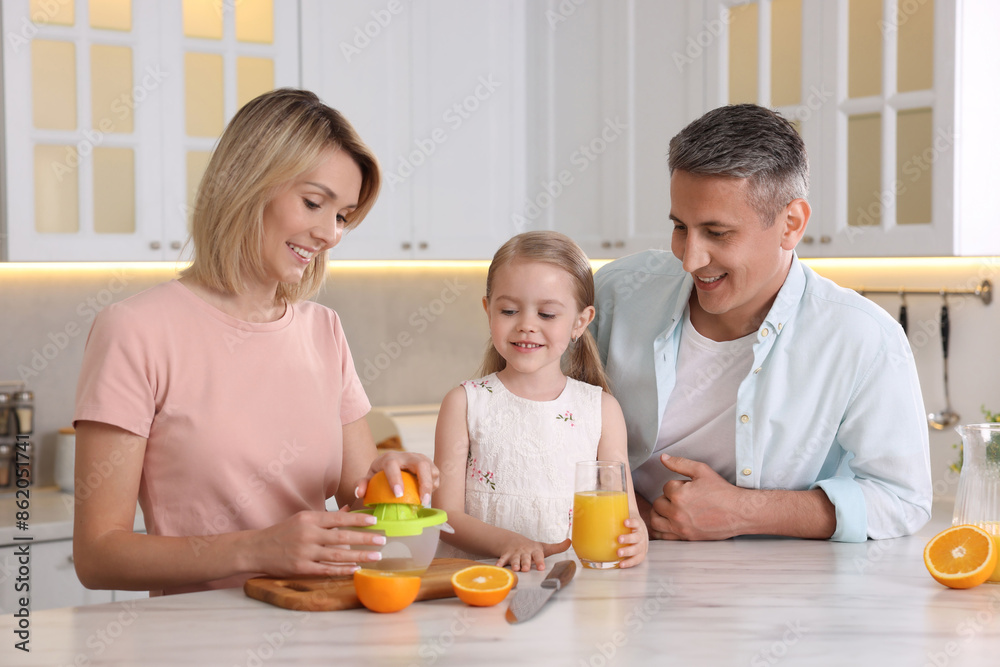 Happy family with juicer and fresh products making juice at white marble table in kitchen Happy family with juicer and fresh products making juice at white marble table in kitchen