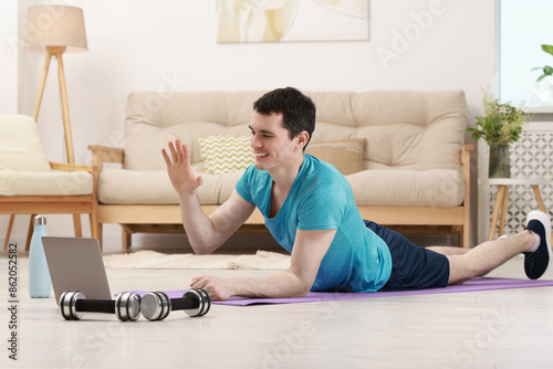 Fotografie Online fitness trainer. Man having video chat via laptop at home