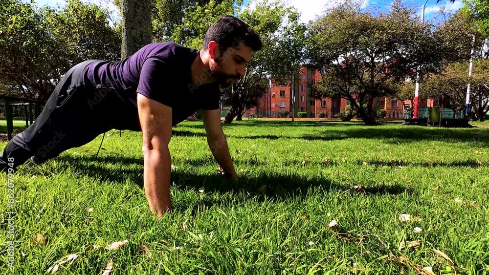 young fitness man doing push up arm exercise in a park in the city