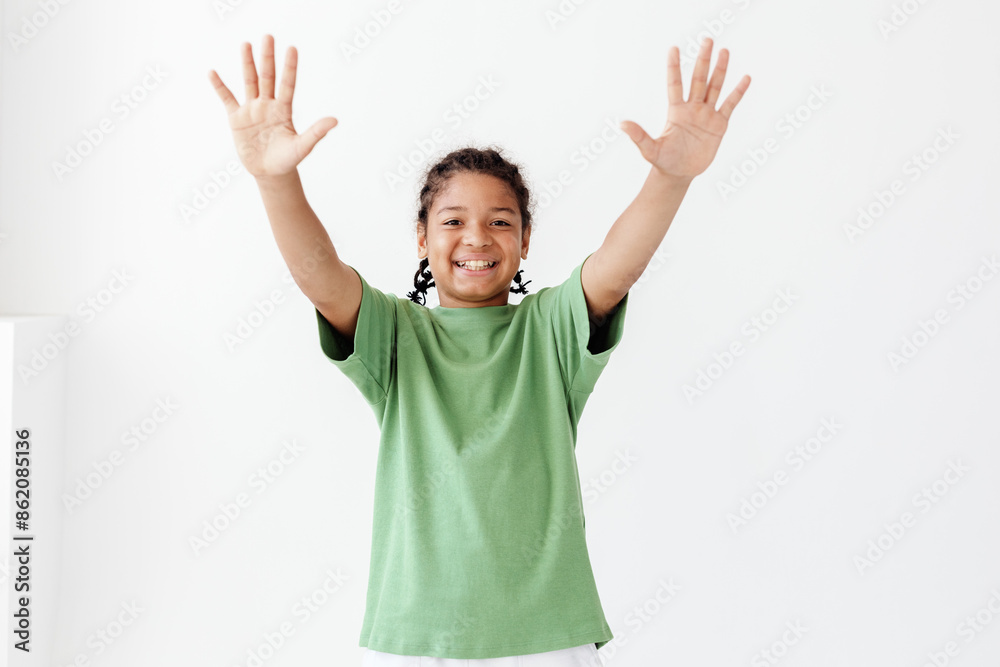 Excited young boy in green tshirt joyfully raising his hands in the air outdoors Excited young boy in green tshirt joyfully raising his hands in the air outdoors
