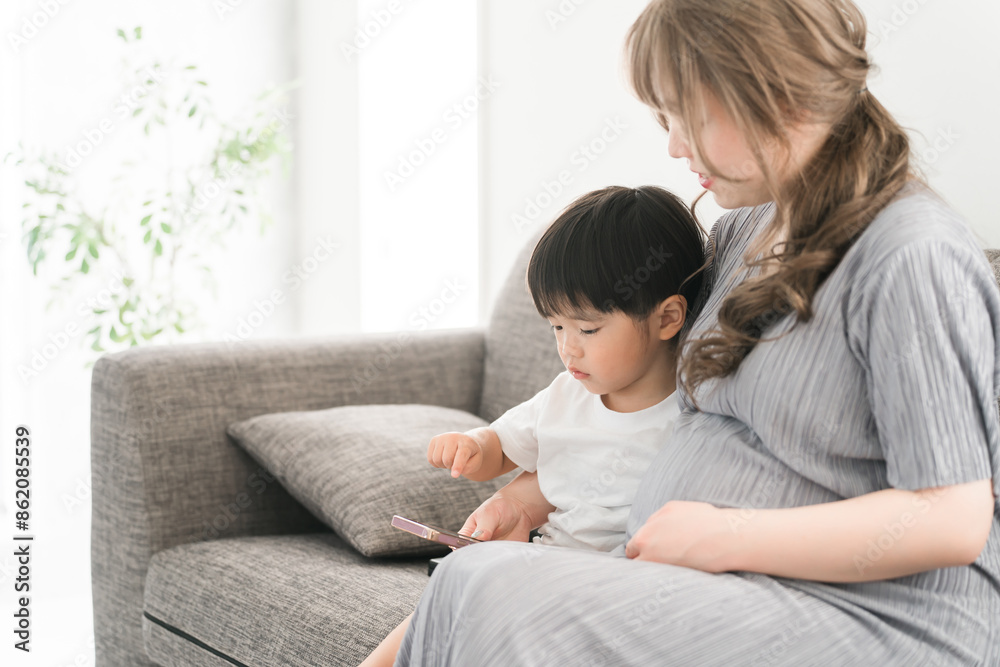 スマホを見る子供と子守をする妊娠中のママ・母親・妊婦
スマホを見る子供と子守をする妊娠中のママ・母親・妊婦