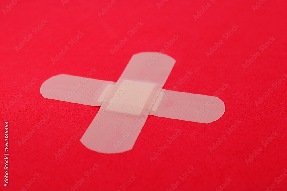 Two expanded band aids forming a cross on a red background Two expanded band aids forming a cross on a red background