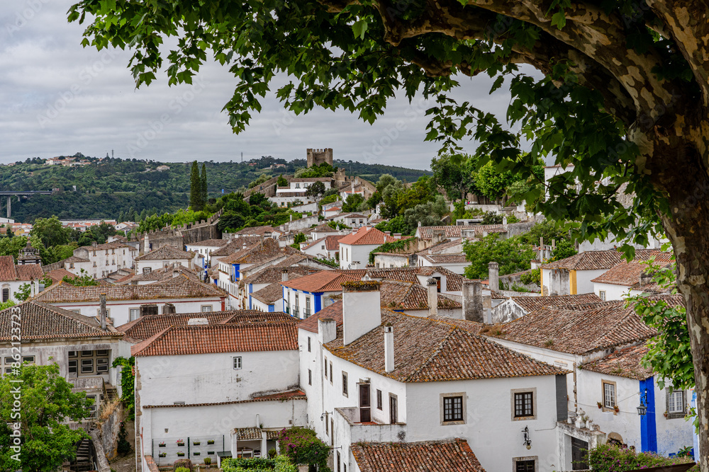 Obraz premium Obidos, Portugal. Cityscape of the town with medieval houses, wall and the Albarra tower. Roofs and castle of Obidos, a medieval town in Portugal
