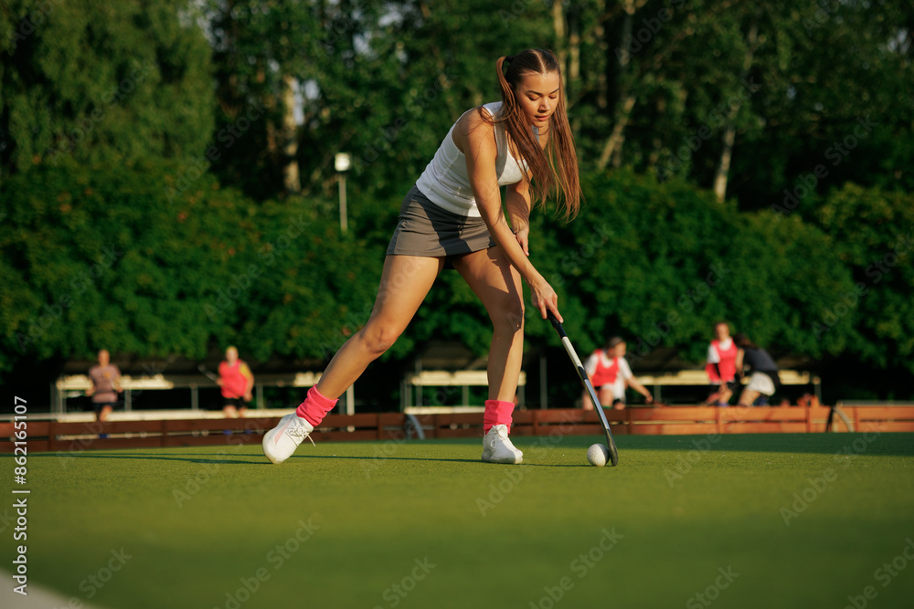 Obraz premium girl hockey player plays field hockey on a sunny day, the hockey player hits the ball with a stick