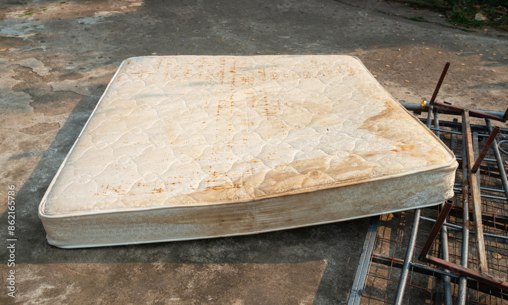 Old mattress on the grass, cement floor, ,Forgotten, rusty, dirty torn old Mattress, Old discarded mattress on the street. Homelessness or poverty. Old mattress on the grass, cement floor, ,Forgotten, rusty, dirty torn old Mattress, Old discarded mattress on the street. Homelessness or poverty.