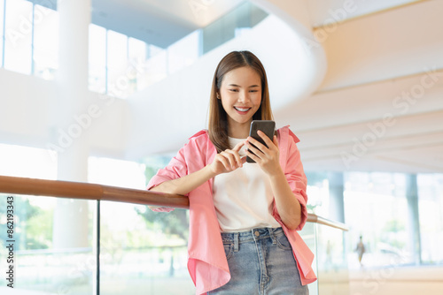 Woman using smartphone in public areas, During leisure time. The concept of using the phone is essential in everyday life. Free Download Woman using smartphone in public areas, During leisure time. The concept of using the phone is essential in everyday life. - GFXLoad