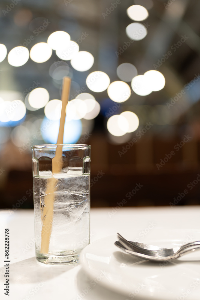 Naklejka premium A clear glass with ice on a bokeh background. Selective focus