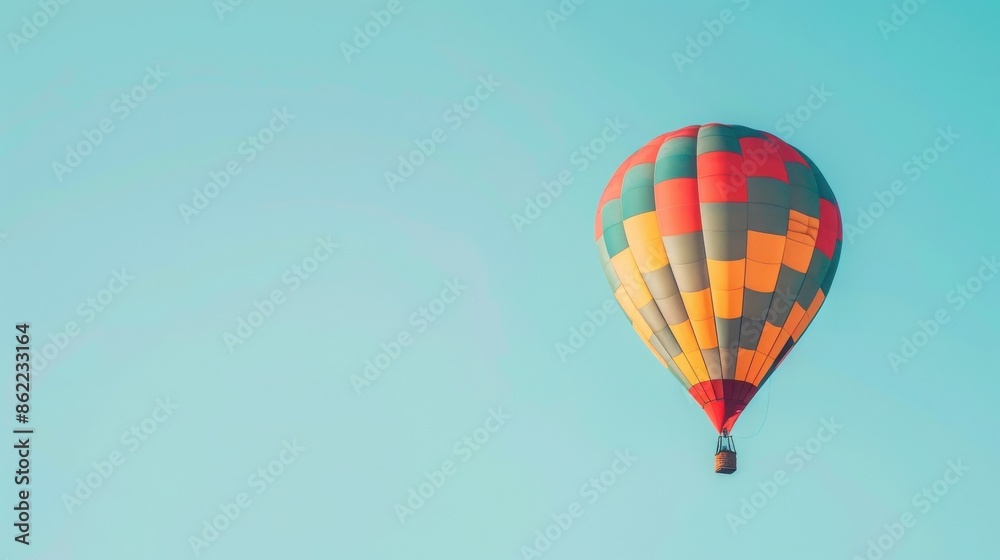 Naklejka premium Colorful hot air balloon floating in the clear blue sky, representing freedom, adventure, and travel on a sunny day.