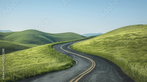 Curving country road through lush green hills under a clear blue sky, ideal for travel and nature themes.