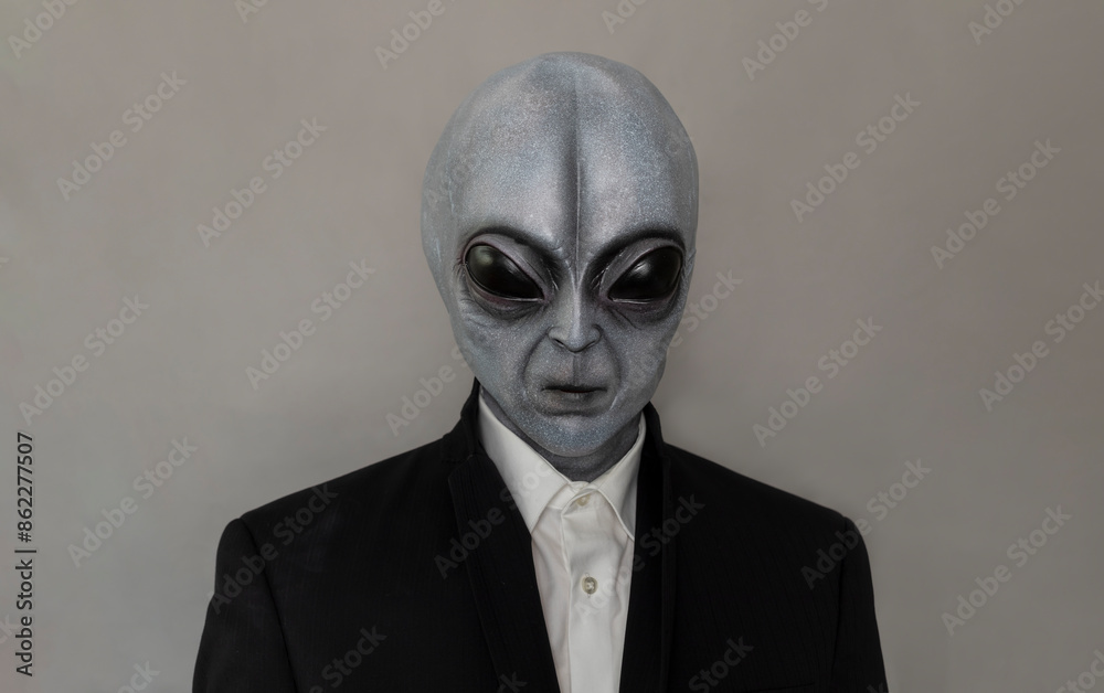 Portrait Of Alien Wearing Suit Gray Background. World UFO Day. Extra Terrestrial Being, Unidentified Flying Objects. Vertical Plane. Grey Humanoid. Portrait Of Alien Wearing Suit Gray Background. World UFO Day. Extra Terrestrial Being, Unidentified Flying Objects. Vertical Plane. Grey Humanoid.