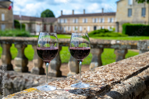 Glasses of french dry red wine in old wine domain on Graves vineyards in Portets village and old castle on background, Bordeaux, France photo