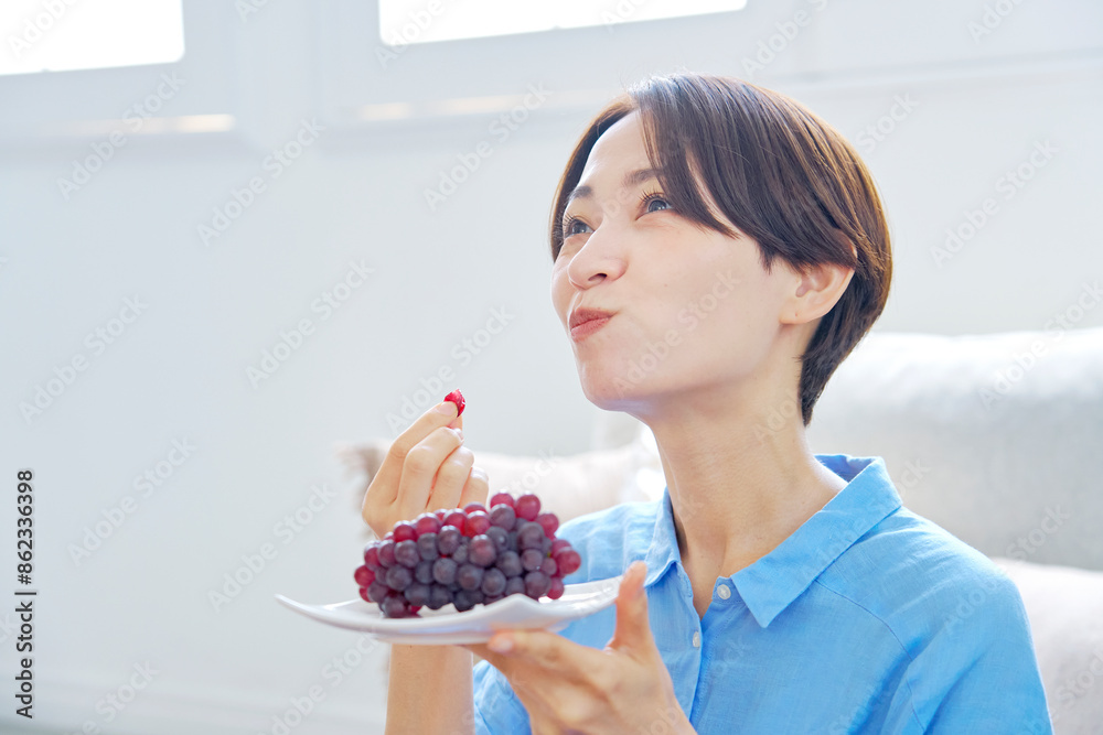 自宅でぶどうを食べる女性 自宅でぶどうを食べる女性