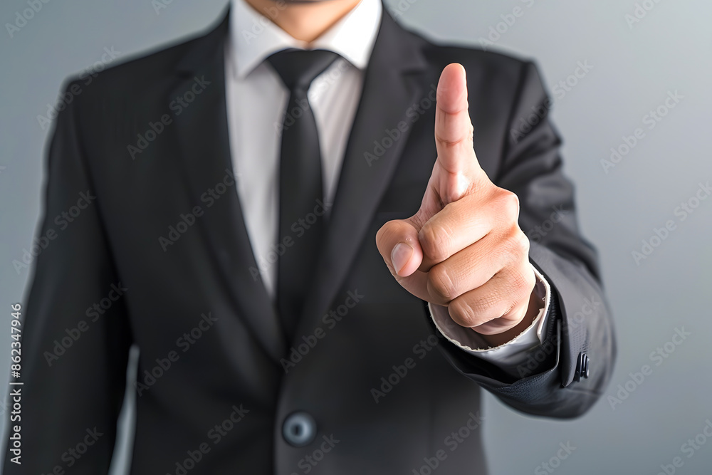 Businessman in a suit pointing a finger forward, suggesting direction or attention. Focus on hand gesture with a blurred background. Businessman in a suit pointing a finger forward, suggesting direction or attention. Focus on hand gesture with a blurred background.