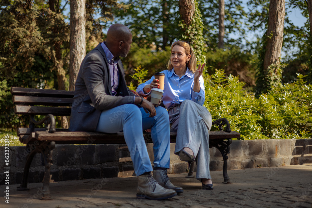 Two people in business clothes having a conversation on a park bench Two people in business clothes having a conversation on a park bench