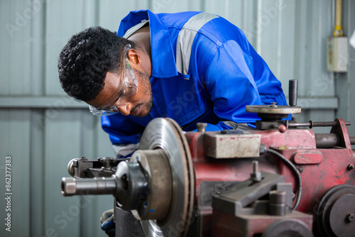 Technician worker man African American wearing uniform safety working machine lathe metal brake disc grinder in factory industrial, worker manufacturing industry concept.
