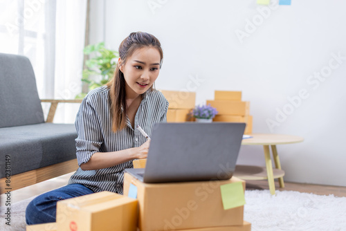 asian young woman owner packing product box prepare to the package for delivery to the customer on sofa at home office asian Entrepreneur SME business concept.