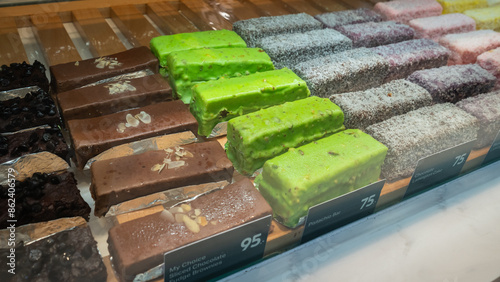 Fudge brownie, pistachio bar and lamington cake in showcase. photo