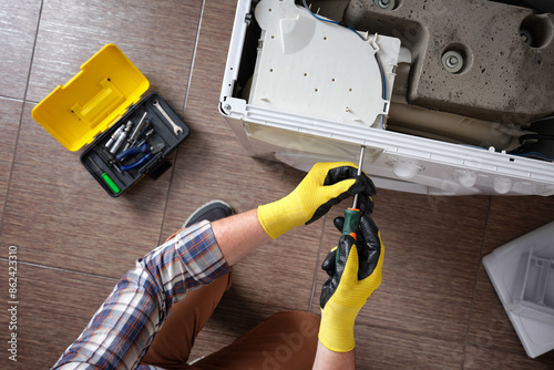 Billede på lærred Close-up of a household appliance repairman disassembling a washing machine with a screwdriver