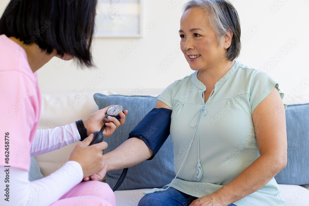 Female nurse checking blood pressure of senior Asian woman at home Female nurse checking blood pressure of senior Asian woman at home
