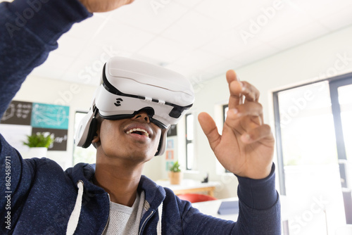Using VR headset, African American male student experiencing virtual reality in classroom photo
