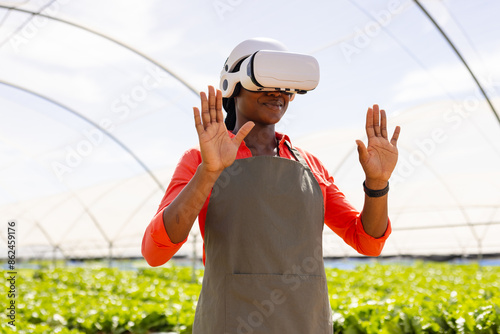 Farmer using VR headset while working in organic hydroponic vegetable greenhouse