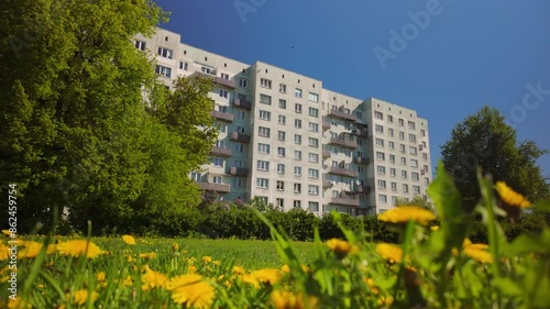Wallpaper Mural Fixed shot captures a Khrushchevka apartment building in Riga with yellow flowers in a grass field during spring, blending urban living with natural beauty. Torontodigital.ca