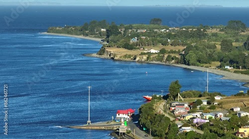 Aerial View capturing a serene coastal Chacao village with blue waters and scattered houses along the coastline. Pull Back Shot photo