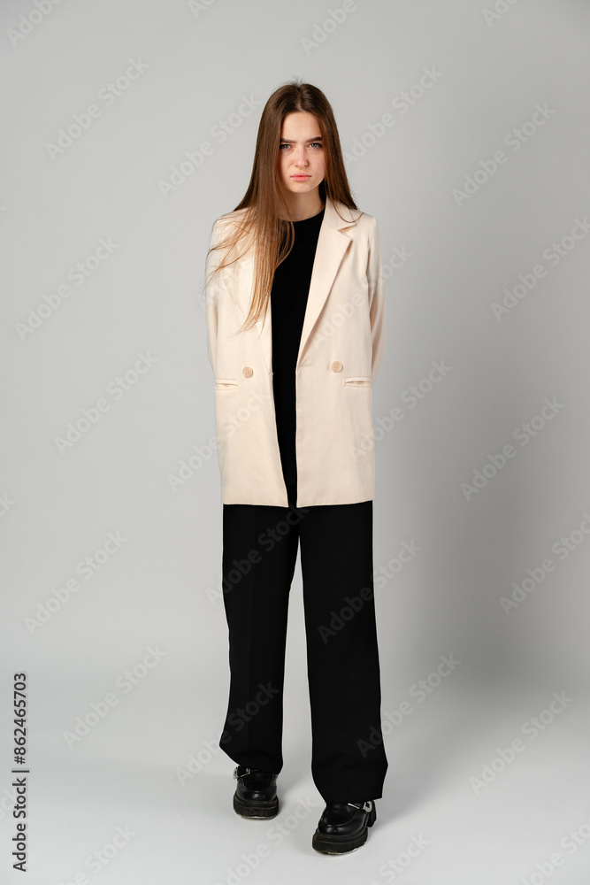 Young Woman in White Jacket and Black Pants on Gray Background. Young Woman in White Jacket and Black Pants on Gray Background.