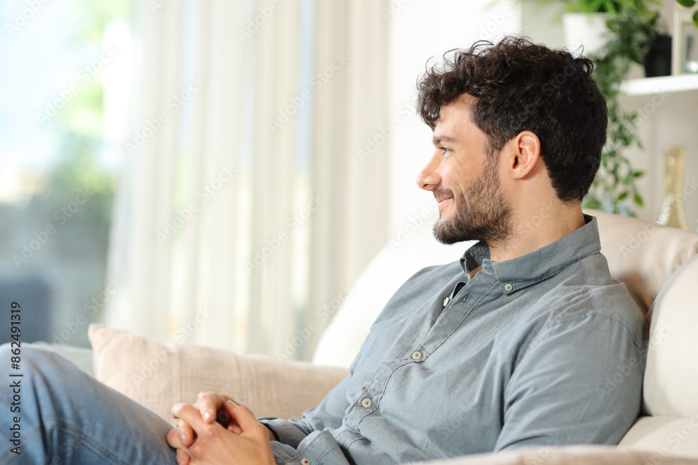 Happy man sitting on a sofa looking through a window Happy man sitting on a sofa looking through a window